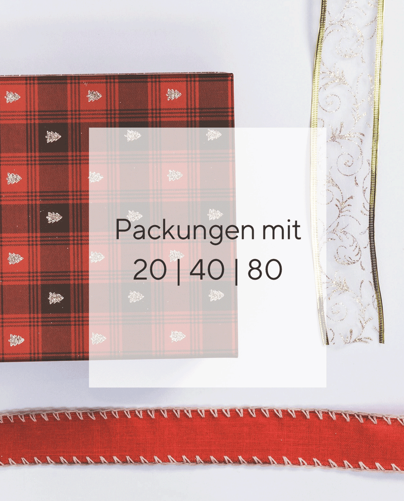 Eine rote karierte Serviette mit kleinen Weihnachtsbaummotiven, ein Stück weißes Geschenkband mit Goldborte und goldenen Aplikationen und ein rotes Geschenkband auf weißem Hintergrund. In der Mitte sind 2 Runde Weihnachtsaufkleber abgebildet. Der obere ist rot mit dem Text "Schöne Weihnachten" und einem Schlitten mit Geschenk als Motiv. Der untere Aufkleber ist Tannengrün, hat den Text " Fröhliche Weihnachten" und einen Schneemann als Motiv.