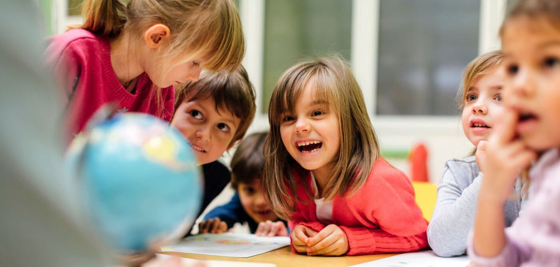 Gruppe glücklicher Kindergartenkinder schauen sich einen Globus an