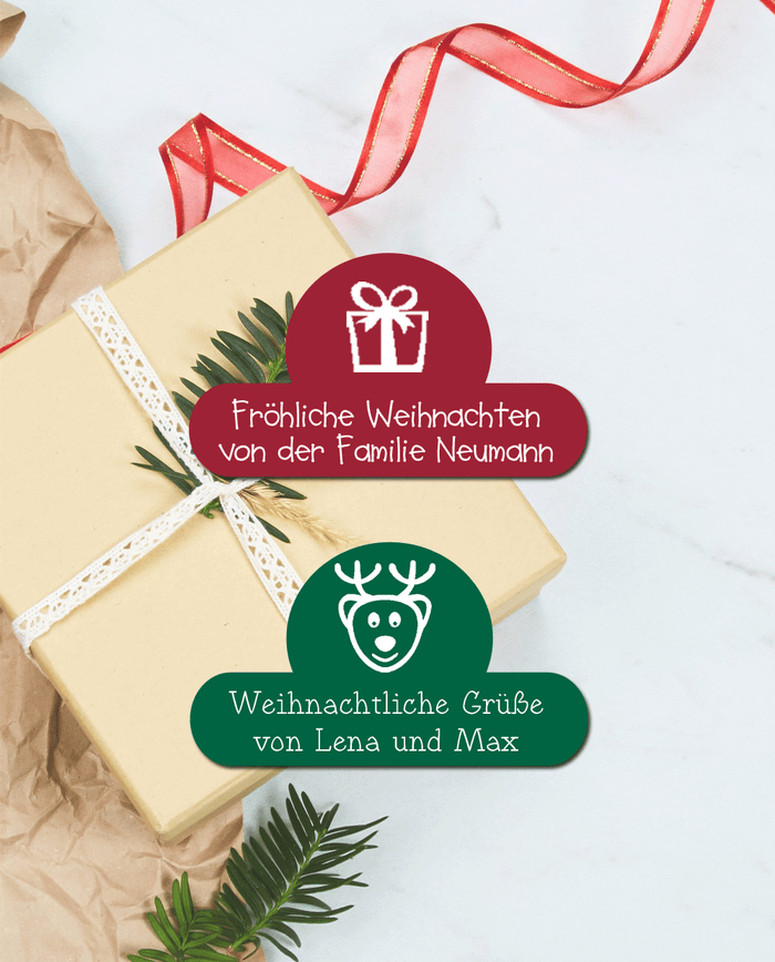 Ein tiefroter und ein dunkelgrüner ballonförmiger Aufkleber mit einem Weihnachtsbild und einem Weihnachtsgruss. Die Aufkleber sitzen auf einem in cremefarbigen eingepacktem Geschenk, ein Weihnachtsbaumzweig steckt in dem weißen umwickeltem Geschenkband. Drumherum liegt etwas braunes Paketpapier und rotes Geschenkband. Der Hintergrund ist hellgrauer Marmor.