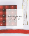 Eine rote karierte Serviette mit kleinen Weihnachtsbaummotiven, ein Stück weißes Geschenkband mit Goldborte und goldenen Aplikationen und ein rotes Geschenkband auf weißem Hintergrund. In der Mitte ist ein durchsichtiges Quadrat mit den Stückzahlen der erhältlichen Packungen, 20, 40 oder 80 Stück angegeben. 