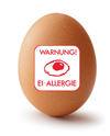 Ein hellbraunes Ei auf weißem Hintergrund. Im Vordergrund ist ein weißer in rotem Text geschriebener Ei-Allergie Warnaufkleber