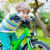 Dunkelblonder Junge, der sich auf den Lenker seines leuchtenden grünen Fahrrads lehnt. Er trägt eine türkisfarbene Hose und ein mehrfarbig gestreiftes Oberteil und schaut lächelnd in die Kamera. Auf dem grünen Rahmen des Fahrrads befindet sich ein mittelblauer Jumbo-Aufkleber, beschriftet mit dem Namen Jack Davidson in der Schriftart School Print und drei Fahrrädern als Motiv. Verschwommen im Hintergrund ist Gras und ein Baumstamm zu sehen. 